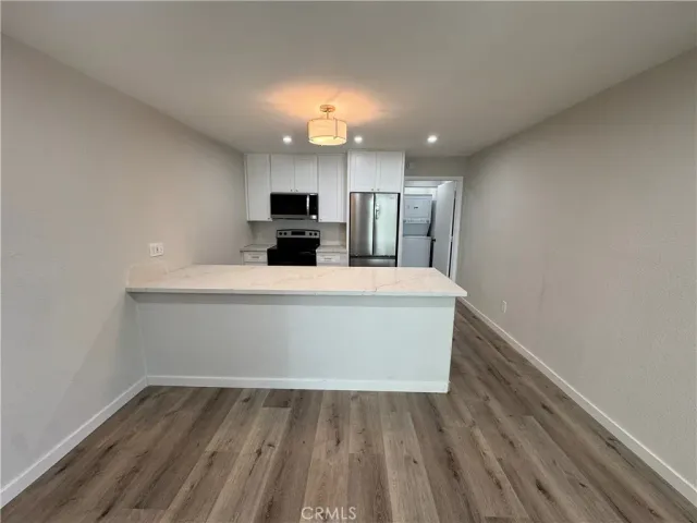 a view of a kitchen with kitchen island a sink wooden floor and a refrigerator