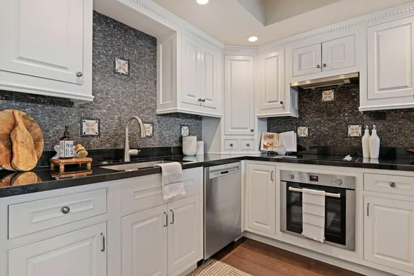 a kitchen with granite countertop white cabinets and white appliances