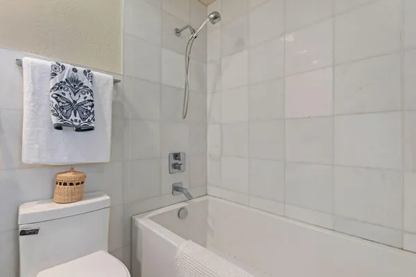 a white bath tub sitting next to a white toilet and vanity