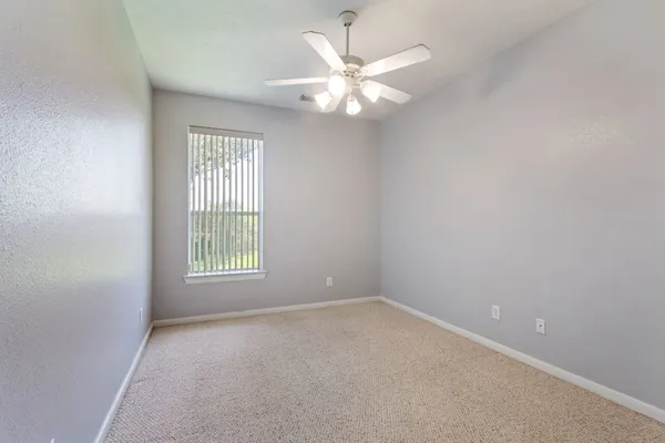 an empty room with windows and chandelier fan