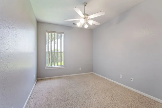 an empty room with windows and chandelier fan