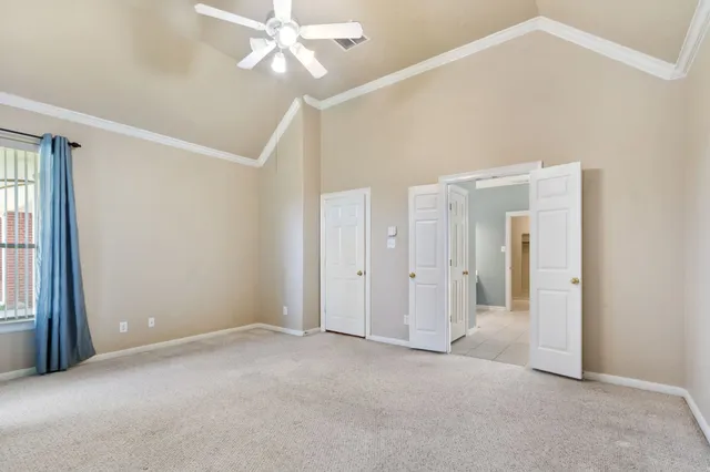 an empty room with chandelier fan and windows