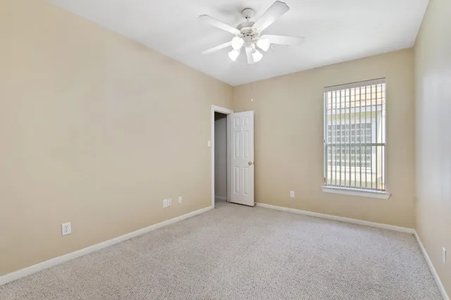 an empty room with chandelier fan and windows