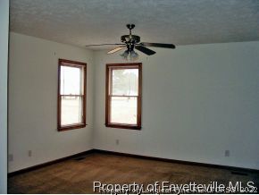 10223 Rockfish Road Raeford, NC 28376 - Photo 10 of 12 an empty room with windows and chandelier fan