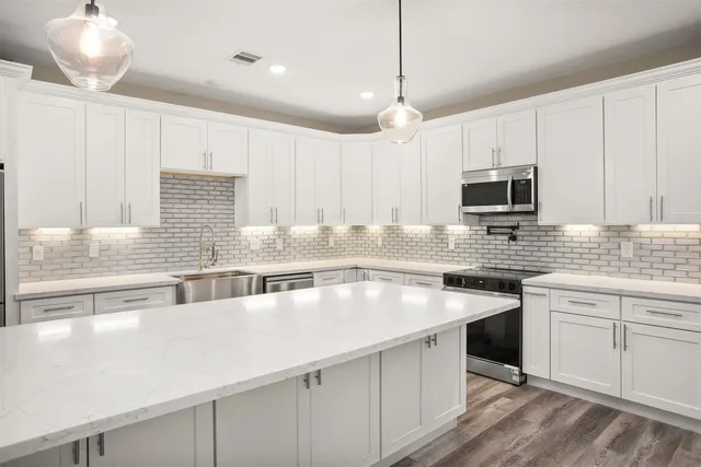 a kitchen with kitchen island granite countertop a sink a counter space appliances and cabinets