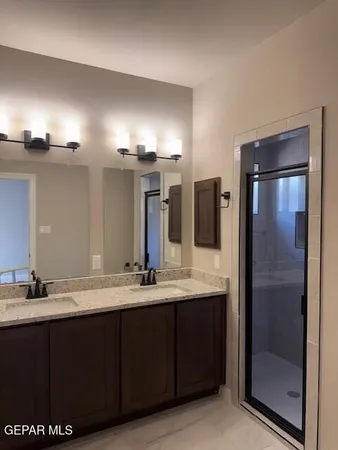 a bathroom with a granite countertop sink a mirror and a shower
