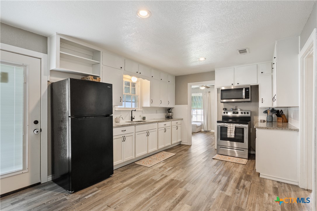 1206 Ashleman Street Waco, TX 76705 - Photo 9 of 26 a kitchen with a refrigerator a stove top oven and wooden floor