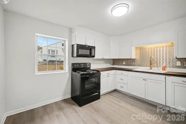 a kitchen with granite countertop a stove a sink and a microwave
