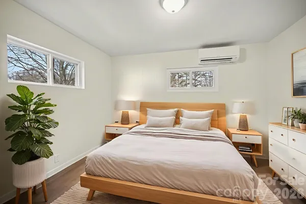 a bedroom with a bed potted plant on dresser and a window