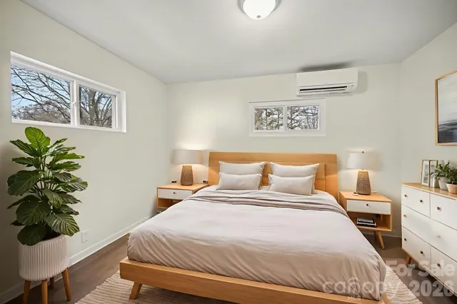 a bedroom with a bed potted plant on dresser and a window