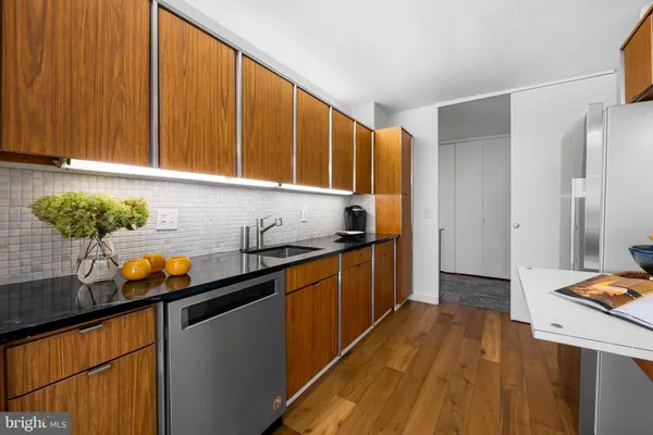 a kitchen with stainless steel appliances a stove a sink dishwasher and white cabinets with wooden floor