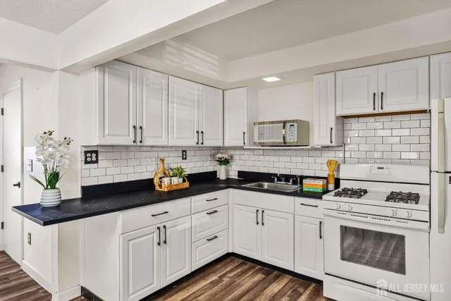 a kitchen with granite countertop white cabinets and white appliances