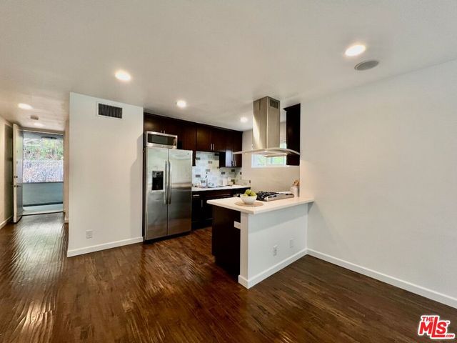 a kitchen with a sink wooden floor and a refrigerator