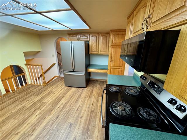 280 Raven Hills Road Colorado Springs, CO 80919 - Photo 26 of 48 Kitchen with appliances with stainless steel finishes, built in study area, light wood finished floors, light brown cabinets, and baseboards