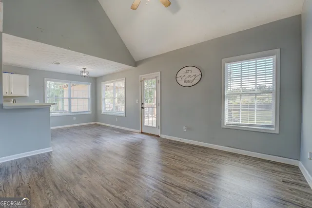 an empty room with wooden floor and windows