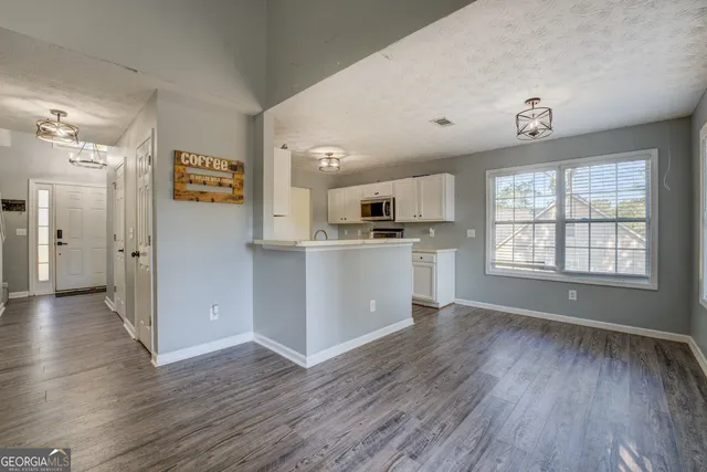 a view of a kitchen with a fridge wooden floor and a window