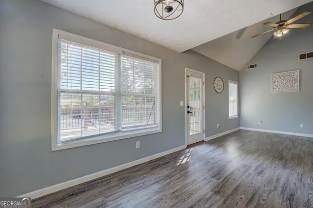 a view of an empty room with wooden floor and a window