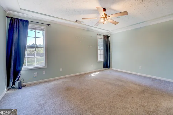 an empty room with windows and ceiling fan