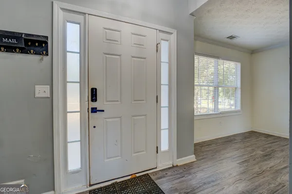 a view of an empty room with wooden floor and a window