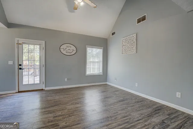 a view of an empty room with wooden floor and a window