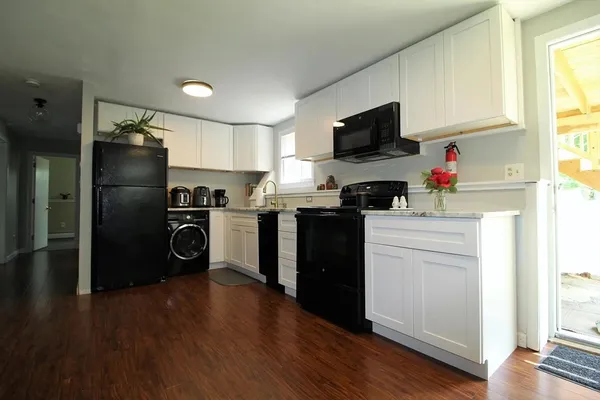 a kitchen with a refrigerator stove and wooden floor