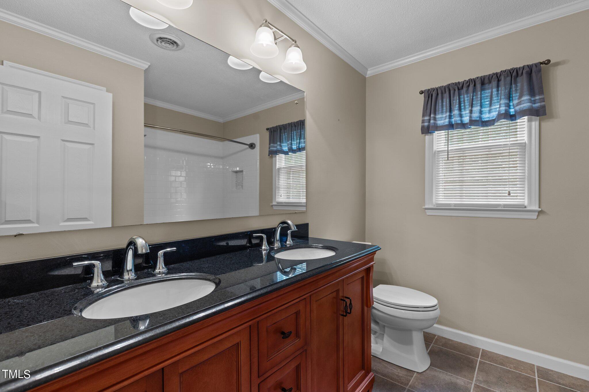 5125 Russell Road Durham, NC 27712 - Photo 33 of 59 a bathroom with a granite countertop sink a toilet and a mirror