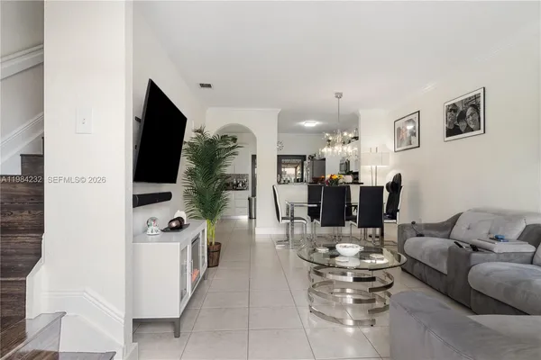 a living room with furniture kitchen view and a flat screen tv