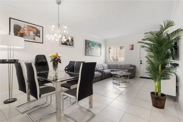 a living room with furniture a chandelier and a potted plant