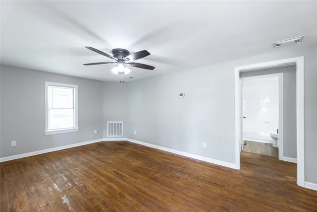an empty room with wooden floor and a ceiling fan