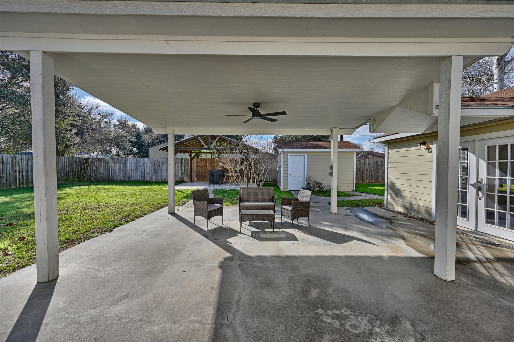 1702 Rampart Street Columbus, TX 78934 - Photo 16 of 38 Fenced backyard featuring a patio area, a shed, french doors, and ceiling fan
