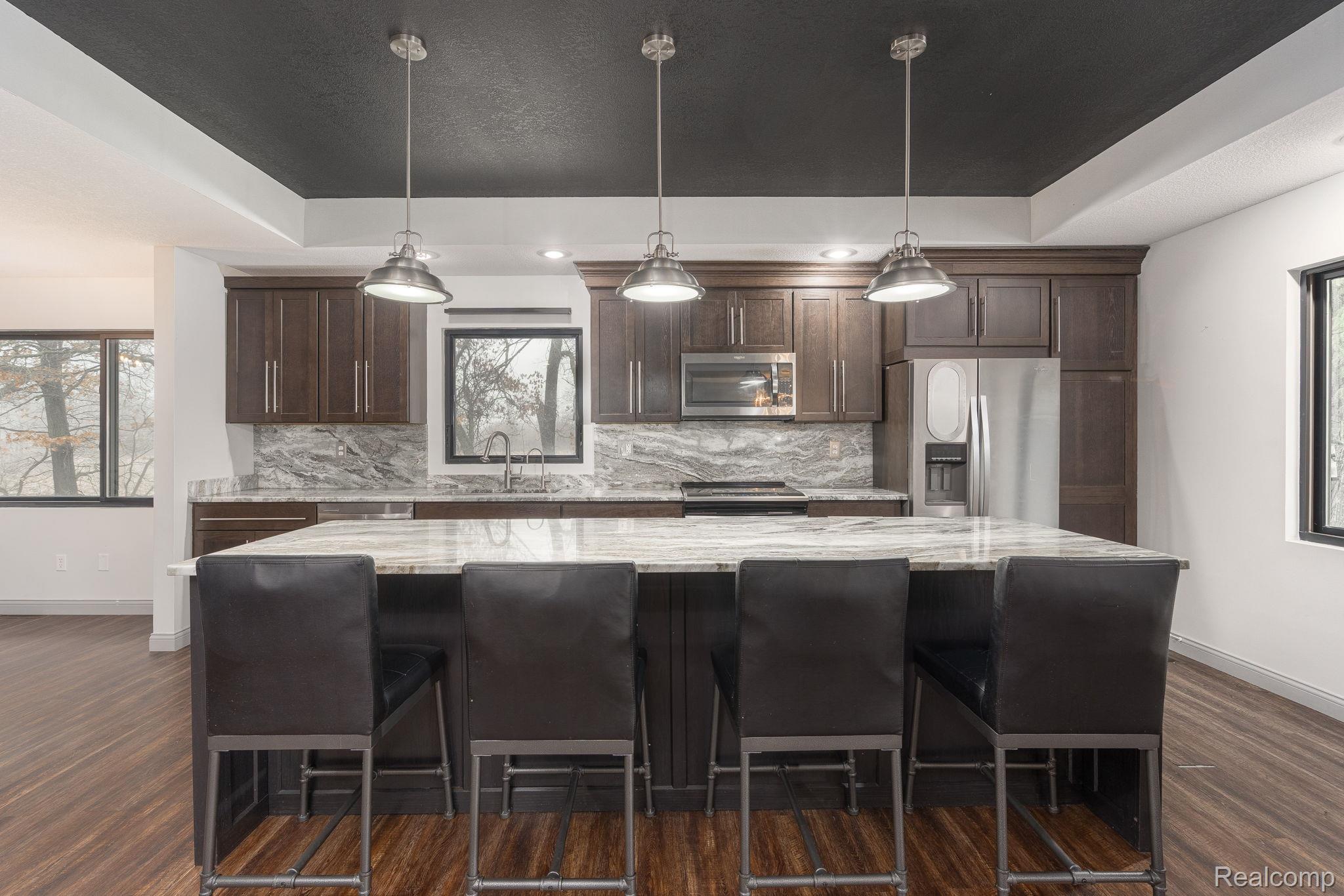 6803 Napoleon Road Jackson, MI 49201 - Photo 25 of 59 Kitchen featuring a raised ceiling, healthy amount of natural light, a kitchen breakfast bar, and dark wood finish cabinets