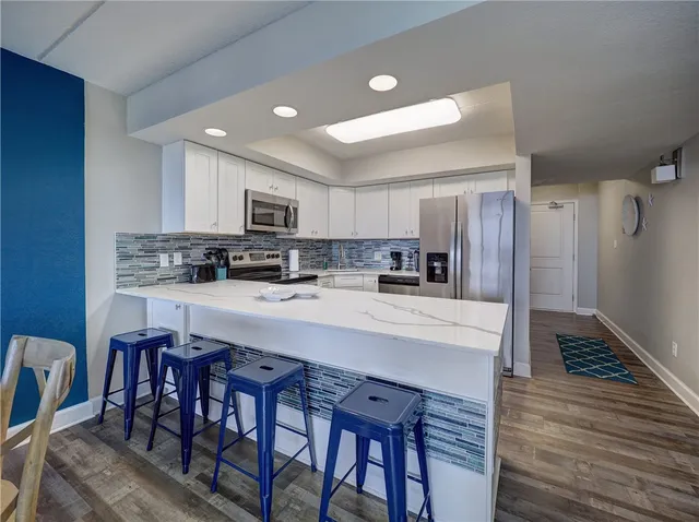 a kitchen with stainless steel appliances granite countertop a microwave a stove a sink dishwasher a refrigerator with a dining table and chairs