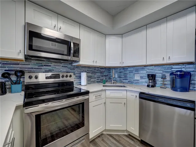 a kitchen with stainless steel appliances a stove microwave and sink