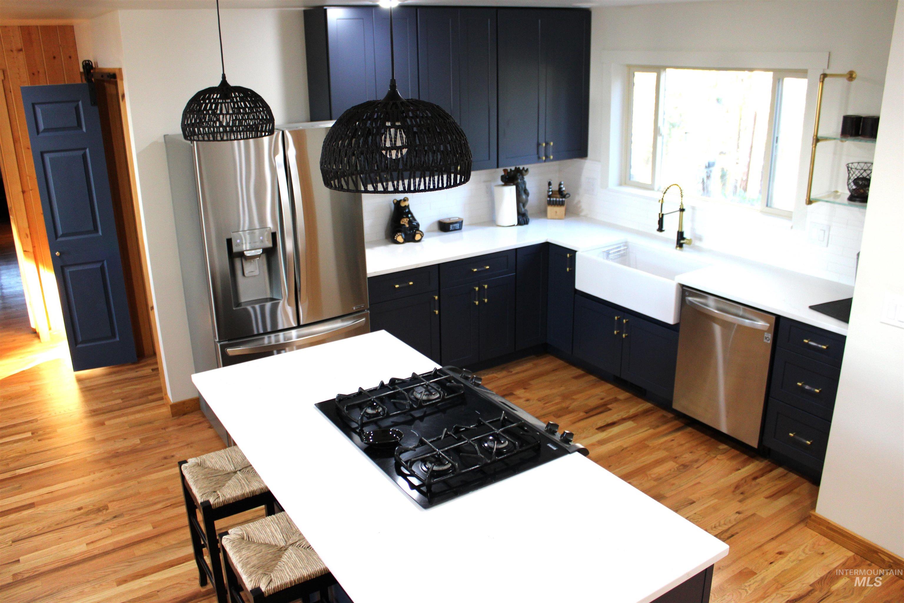 31 Rainbow Ridge Road Garden Valley, ID 83622 - Photo 10 of 33 Kitchen with quartz counter tops, open shelving, stainless steel appliances, light wood flooring, a kitchen island, subway tile backsplash, and propane range.