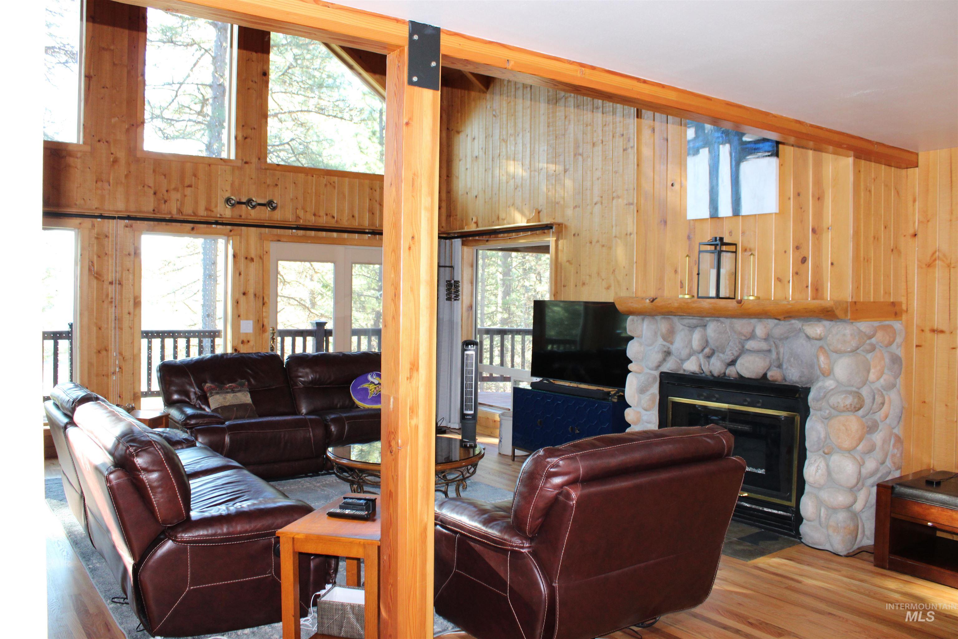 31 Rainbow Ridge Road Garden Valley, ID 83622 - Photo 12 of 33 Great room featuring wooden walls, wood floors, a high ceiling, a fireplace, ceiling fan and sliding doors