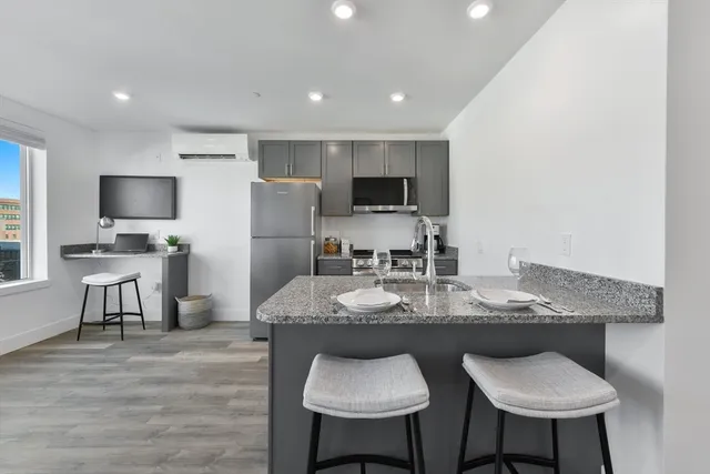 a kitchen with kitchen island granite countertop a sink and a refrigerator