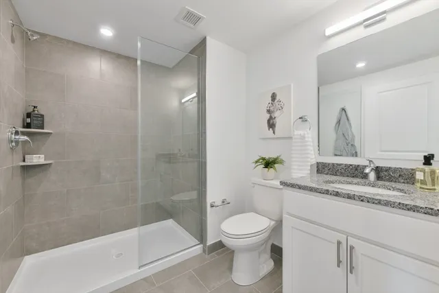 a bathroom with a granite countertop sink a toilet and shower