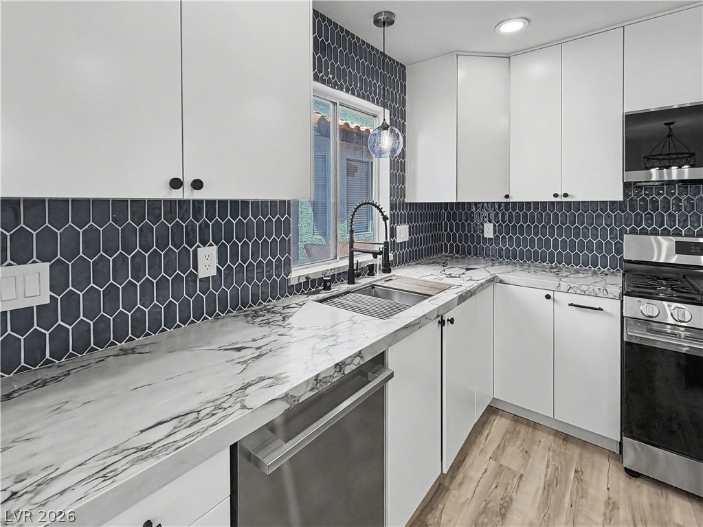 8977 Paige Rene Court Las Vegas, NV 89117 - Photo 8 of 31 A well-appointed kitchen showcasing elegant marble-patterned countertops and sleek, geometric tile backsplash.