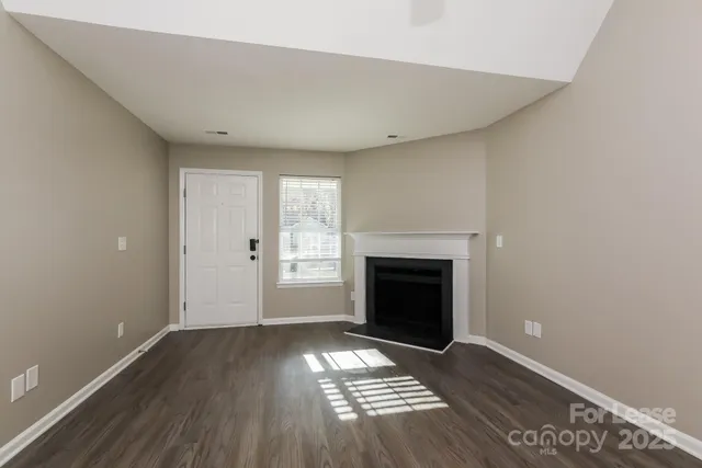an empty room with wooden floor a fireplace and windows