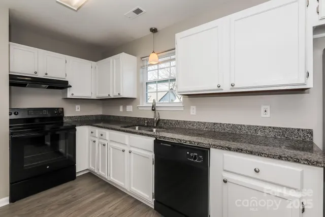 a kitchen with granite countertop white cabinets and a stove