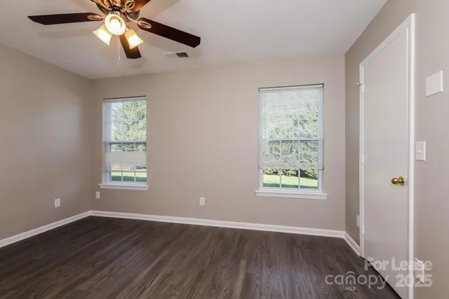a view of an empty room with wooden floor and window
