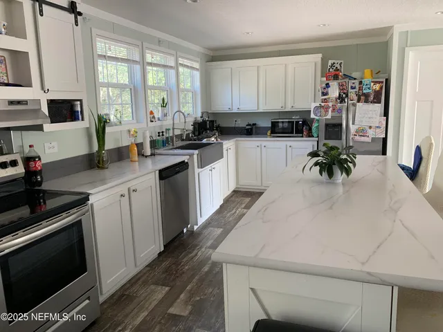 a kitchen with a sink white cabinets and black appliances