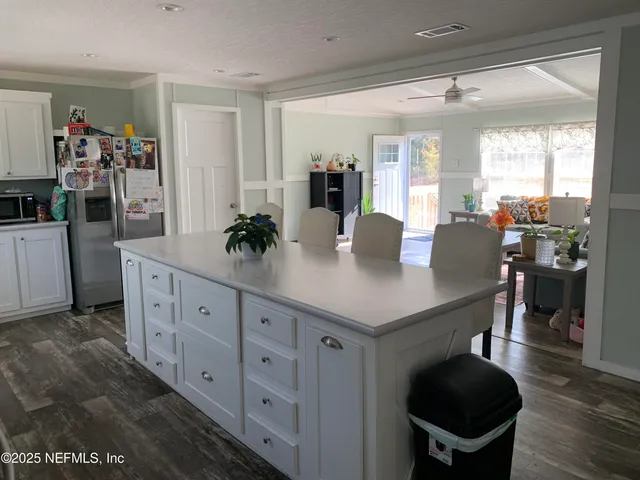 a kitchen with stainless steel appliances a dining table chairs and white cabinets