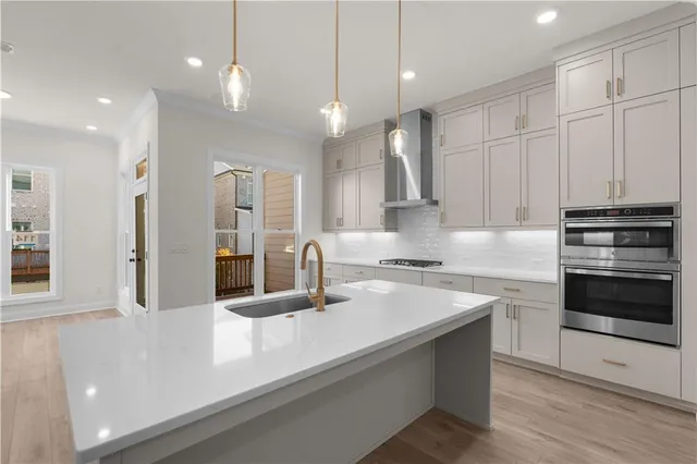 a large white kitchen with a sink dishwasher a stove and white cabinets with wooden floor