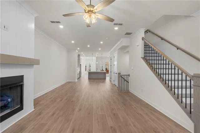 a view of a room with wooden floor a ceiling fan and staircase