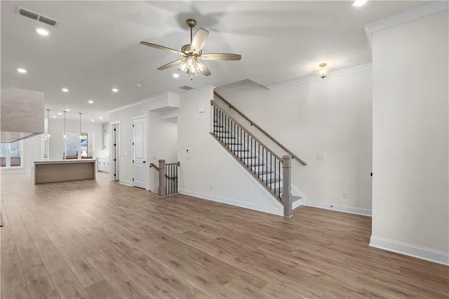 an empty room with wooden floor a fireplace a ceiling fan and windows
