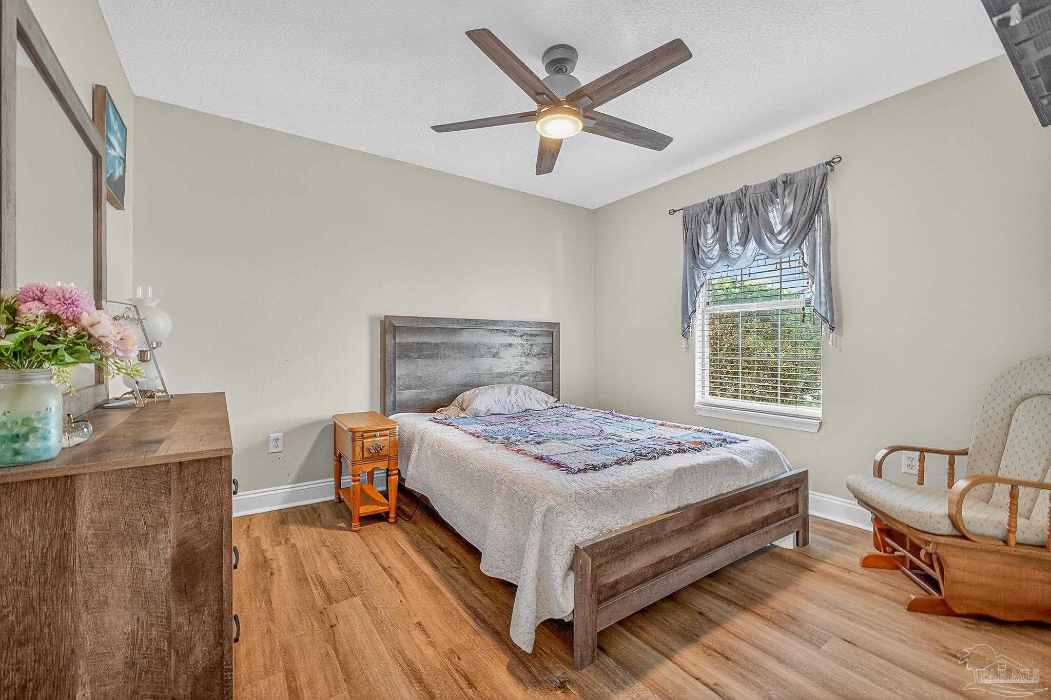 5361 Willard Norris Road Milton, FL 32570 - Photo 35 of 51 a bedroom with a bed table chair and a window