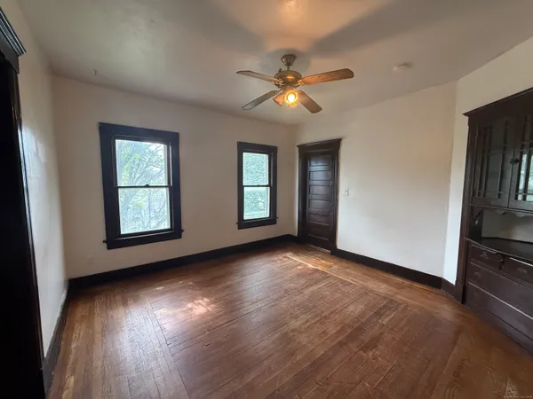 a view of an empty room with window and wooden floor
