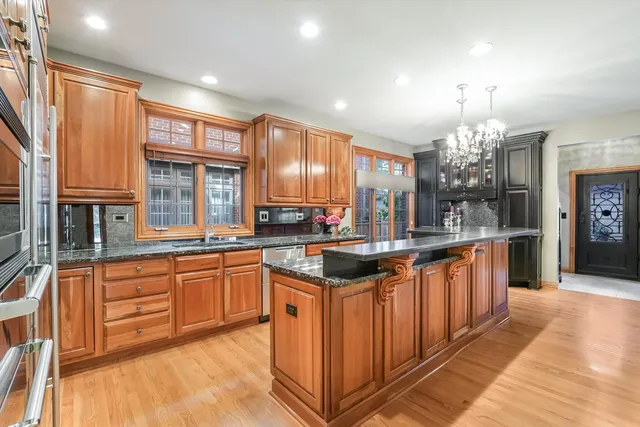 a kitchen with stainless steel appliances granite countertop a stove a sink and a wooden cabinets
