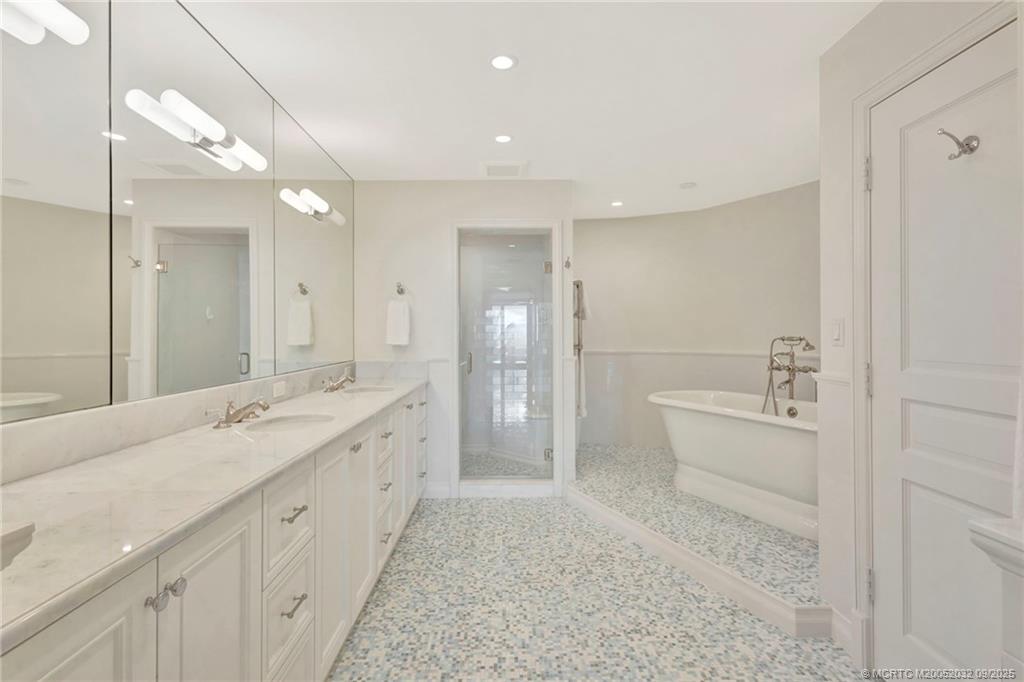 2001 Southeast Sailfish Point Boulevard, Unit 303 Stuart, FL 34996 - Photo 30 of 63 a spacious bathroom with a granite countertop sink a toilet a large mirror a shower and vanity